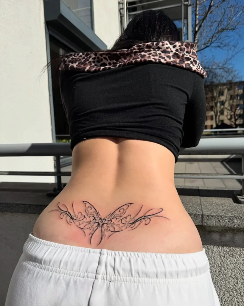 Lower back tattoo with a butterfly formed from intricate scrollwork and swirling lines, blending elegance and artistry.