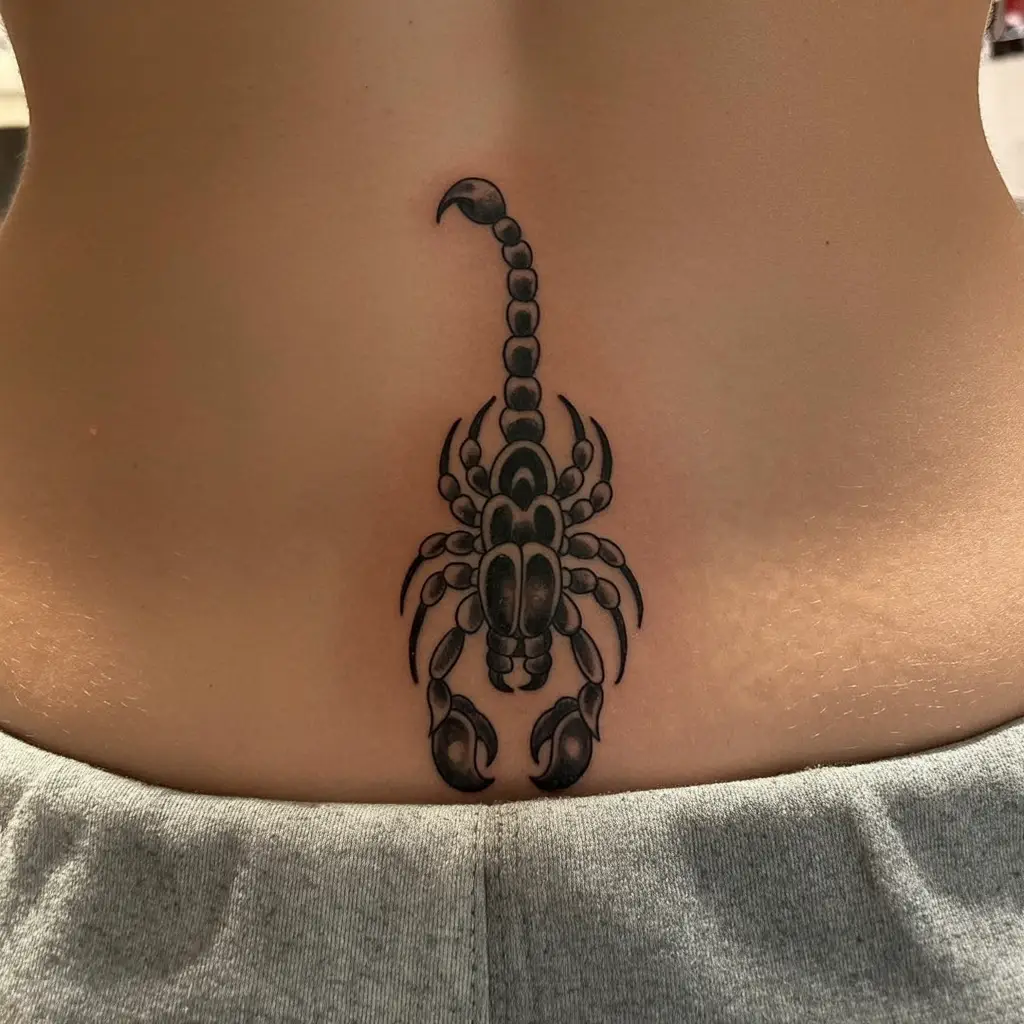  Lower back tattoo featuring a black and gray scorpion with intricate shading and bold details.