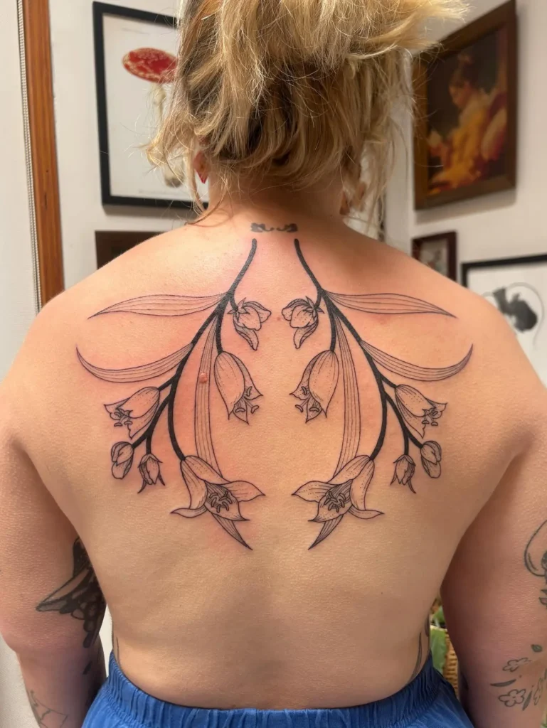 Bellflower back tattoo design for women with graceful floral lines symbolizing emotional healing and elegance

