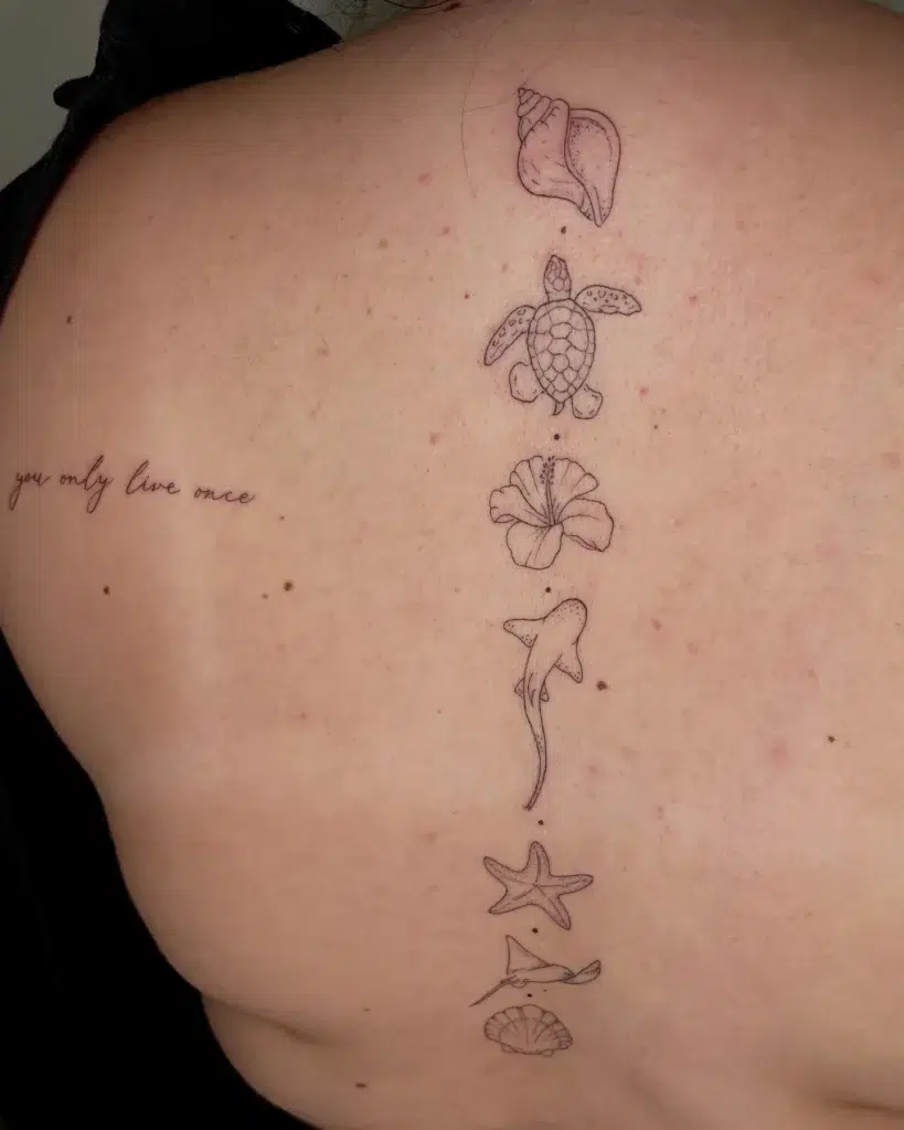 An ocean-themed spine tattoo with a shell, turtle, hibiscus, shark, starfish, ray, and shell in a vertical line down a woman’s back.