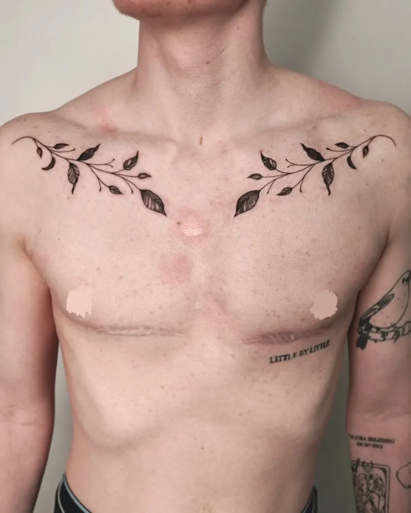 Minimalist chest tattoo for men with fine black-inked branches and leaves extending along the collarbones; symmetrical, simple design symbolizing growth and healing while complementing the chest’s natural shape.