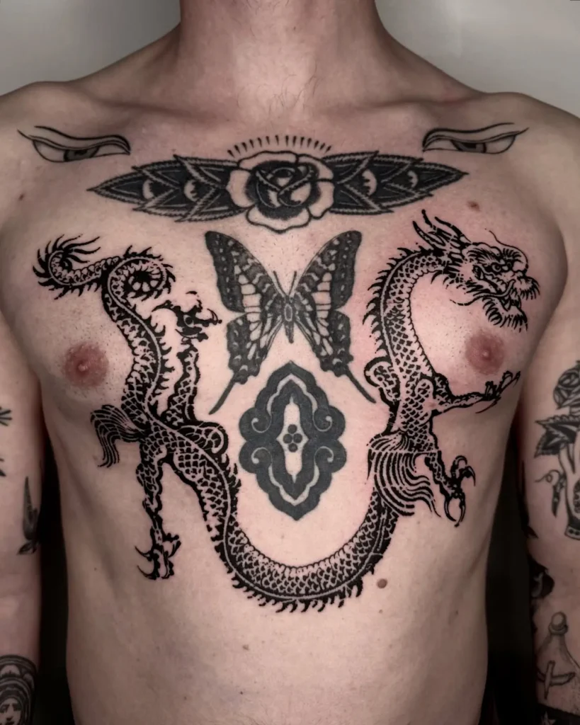 Chest tattoo for men featuring two symmetrical black dragons, a central butterfly, ornamental patterns, and a crowned rose; combines Eastern and Western tattoo styles to represent power, transformation, and unity.