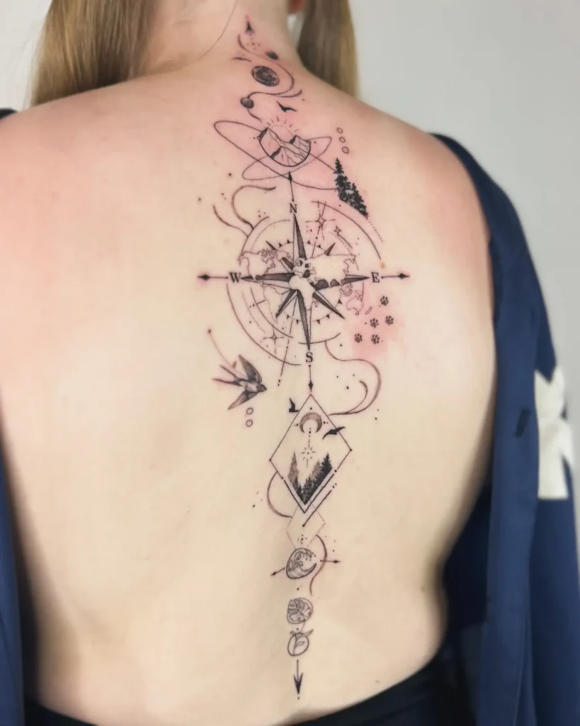 A spine tattoo featuring a compass rose, world map, planets, nature scenes, and fine-line adventure motifs running down a woman’s back.
