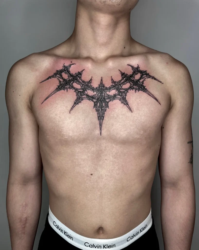 Black abstract chest tattoo for men featuring a jagged, symmetrical crown-like shape with bio-mechanical and spiked detailing; centered high on the chest for a bold, futuristic, and geometric impression.