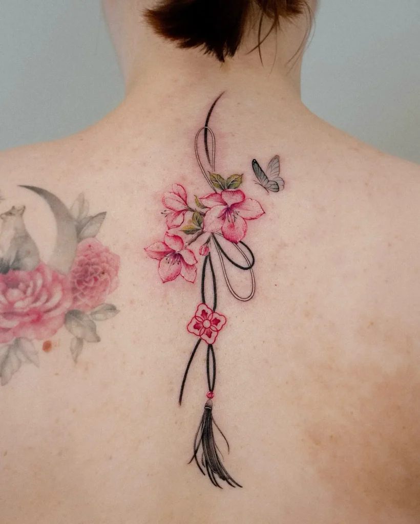 Delicate cherry blossom and tassel back tattoo with butterfly, symbolizing femininity, tradition, and graceful beauty

