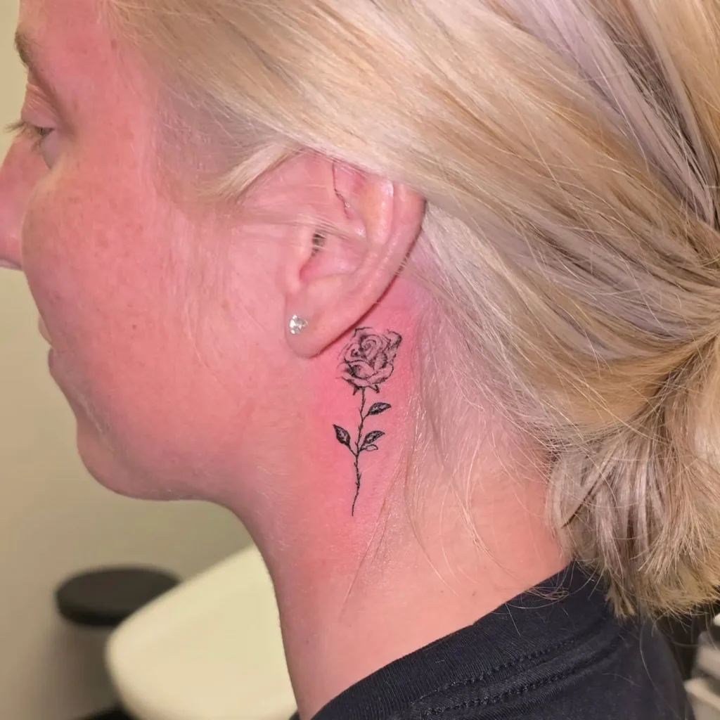 Minimalist black line wave tattoo on the inner arm of a woman, drawn with a single fluid curve.
