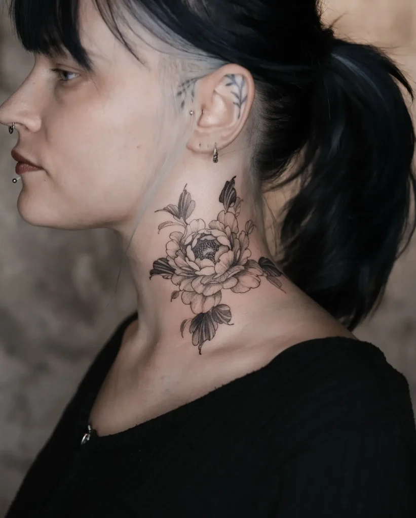 Black and gray peony flower tattoo on side of throat, floral neck tattoos for women with shaded petals and elegant feminine details.