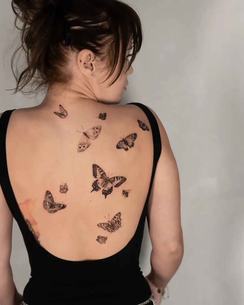 Realistic butterfly tattoos scattered across the upper and lower back. Soft black and grey ink with detailed shading on each butterfly. Feminine, nature-inspired piece, perfect for animal tattoo ideas simple and airy. Great choice for those seeking animal tattoo ideas sleeve alternatives or large expressive back tattoos with meaning and movement.








