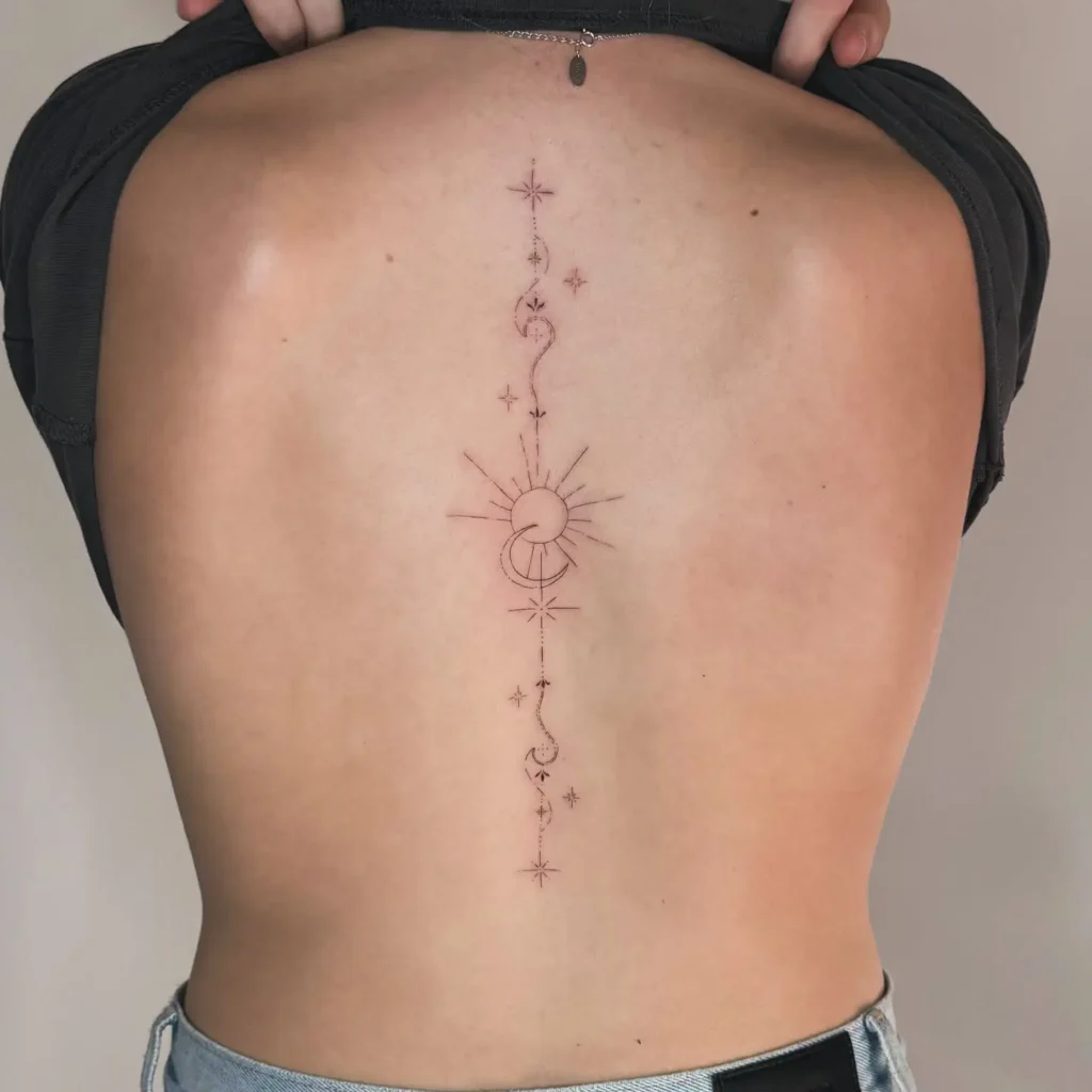 A minimalist spine tattoo featuring a crescent moon, delicate leaves, and small stars in a vertical line on a woman’s back.