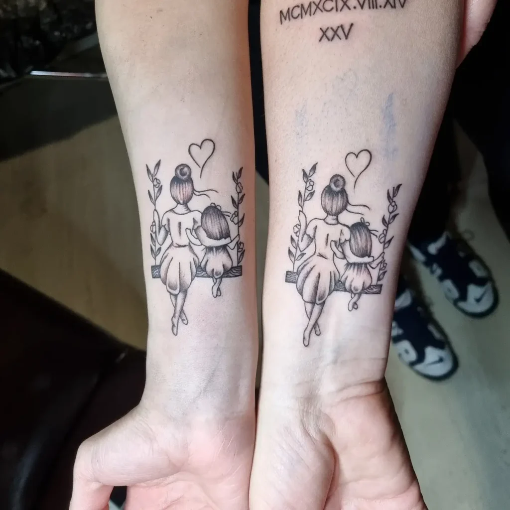 Matching mother and daughter swing tattoos on two wrists, featuring a woman and a little girl sitting side by side on a floral swing, viewed from behind, with a small heart above them. The design symbolizes the close bond and cherished memories between a mother and her child.