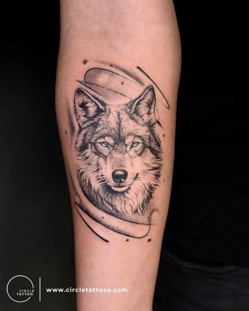 Forearm wolf tattoo with icy blue eyes and sketch-style black ink detailing. Surrounded by abstract linework and soft dot accents. Symbolizes strength, independence, and protection. Fits well for animal tattoo ideas arm or sleeve. A powerful, expressive design mixing realism with artistic edge.








