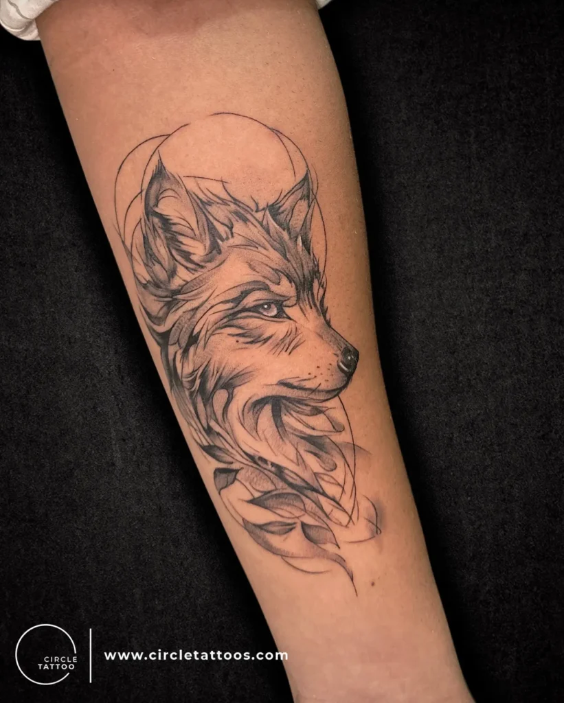 Forearm tattoo of a peaceful wolf head with flowing fur and leaf accents, inked in soft black shading. Features curved lines and subtle realism. Ideal for animal tattoo ideas arm or forearm styles, blending natural strength and grace. Minimal yet expressive design for those who want something balanced, wild, and meaningful.








