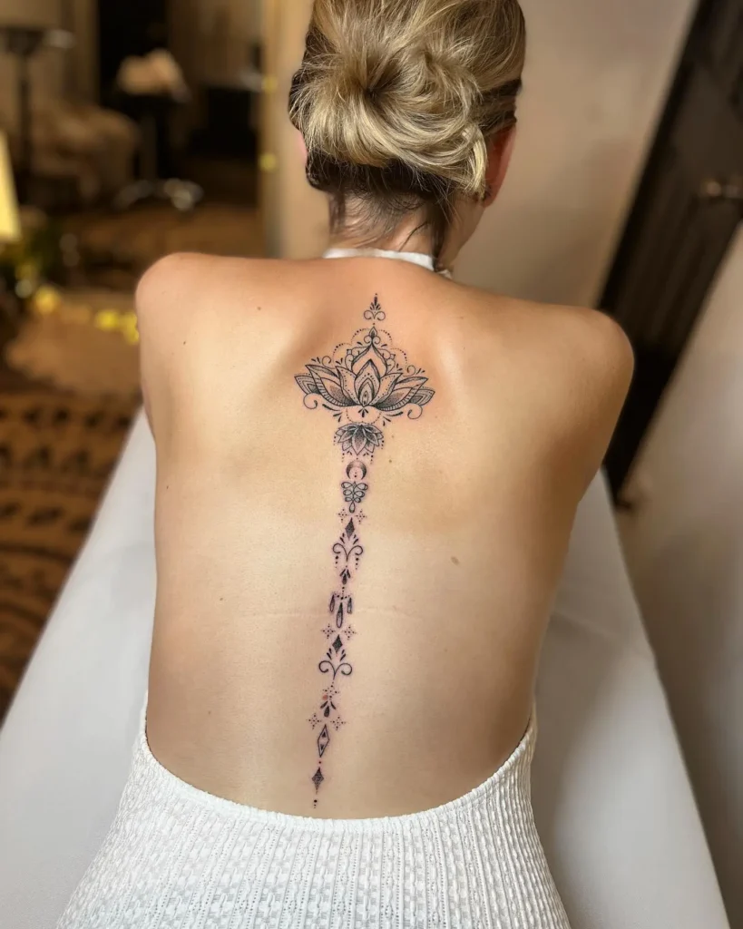 A large mandala lotus spine tattoo with intricate patterns and geometric accents running down a woman’s back.