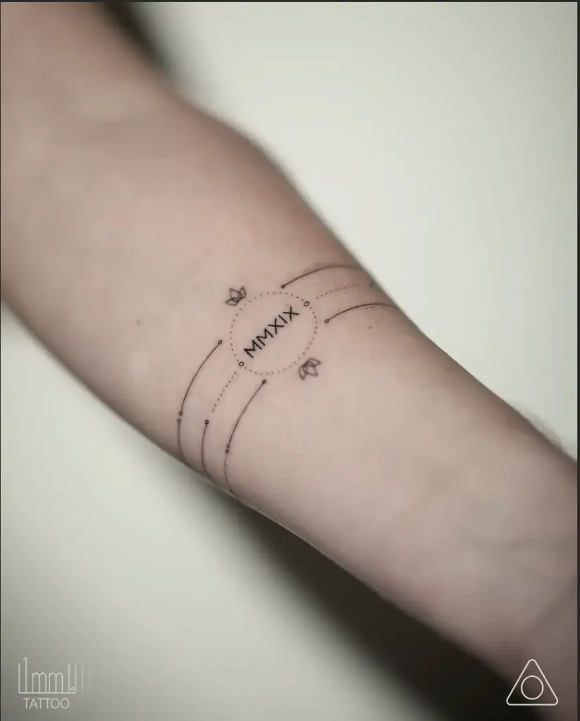  Fine line wrist tattoo featuring a dotted armband with stars and cosmic curves, symbolizing rebirth and personal growth.

