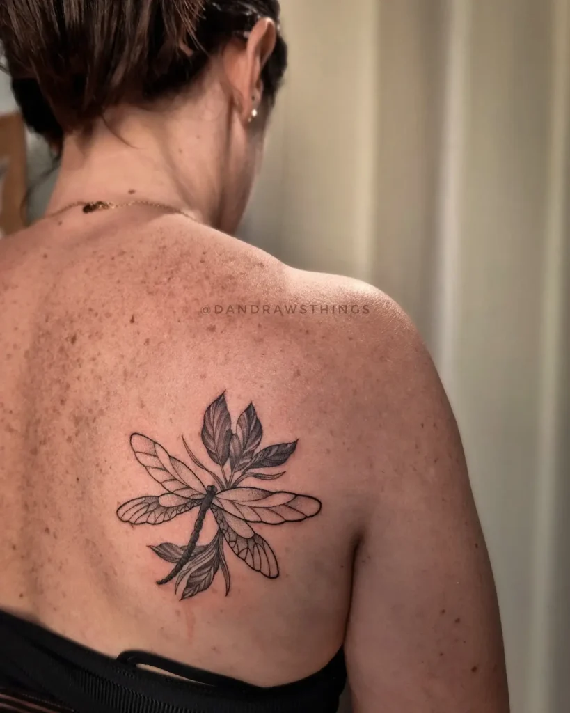 Dragonfly and leaf back tattoo for women, blending nature and transformation in an elegant botanical design

