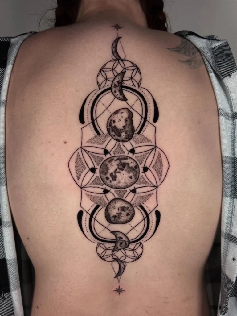 A geometric spine tattoo featuring moon phases, dotwork shading, and intricate lines down the center of a woman’s back.