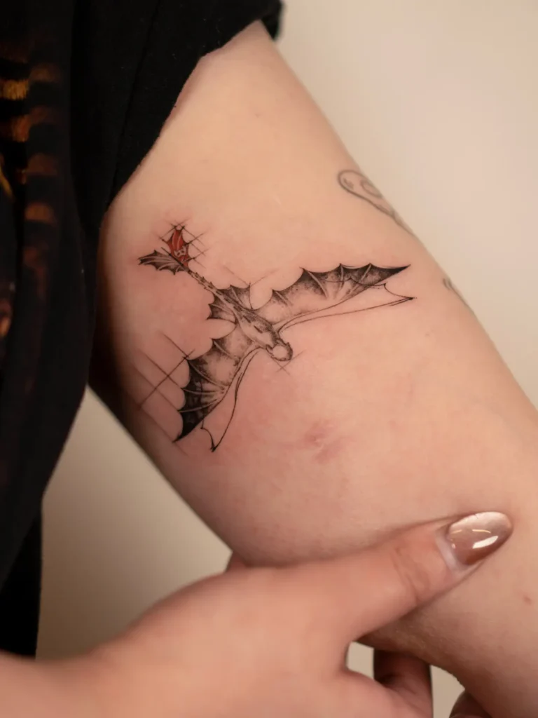 11. Tiny Flying Dragon Arm Tattoo