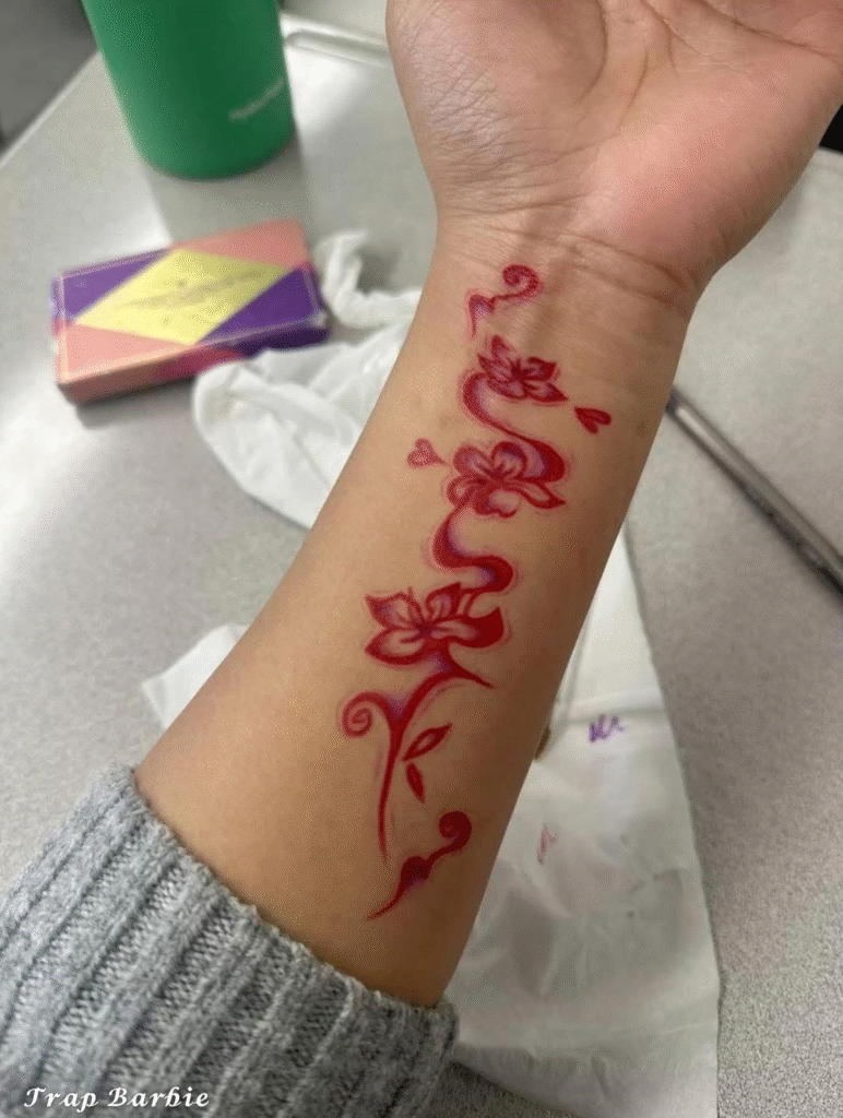 25. Red Ink Floral Script Tattoo on Wrist